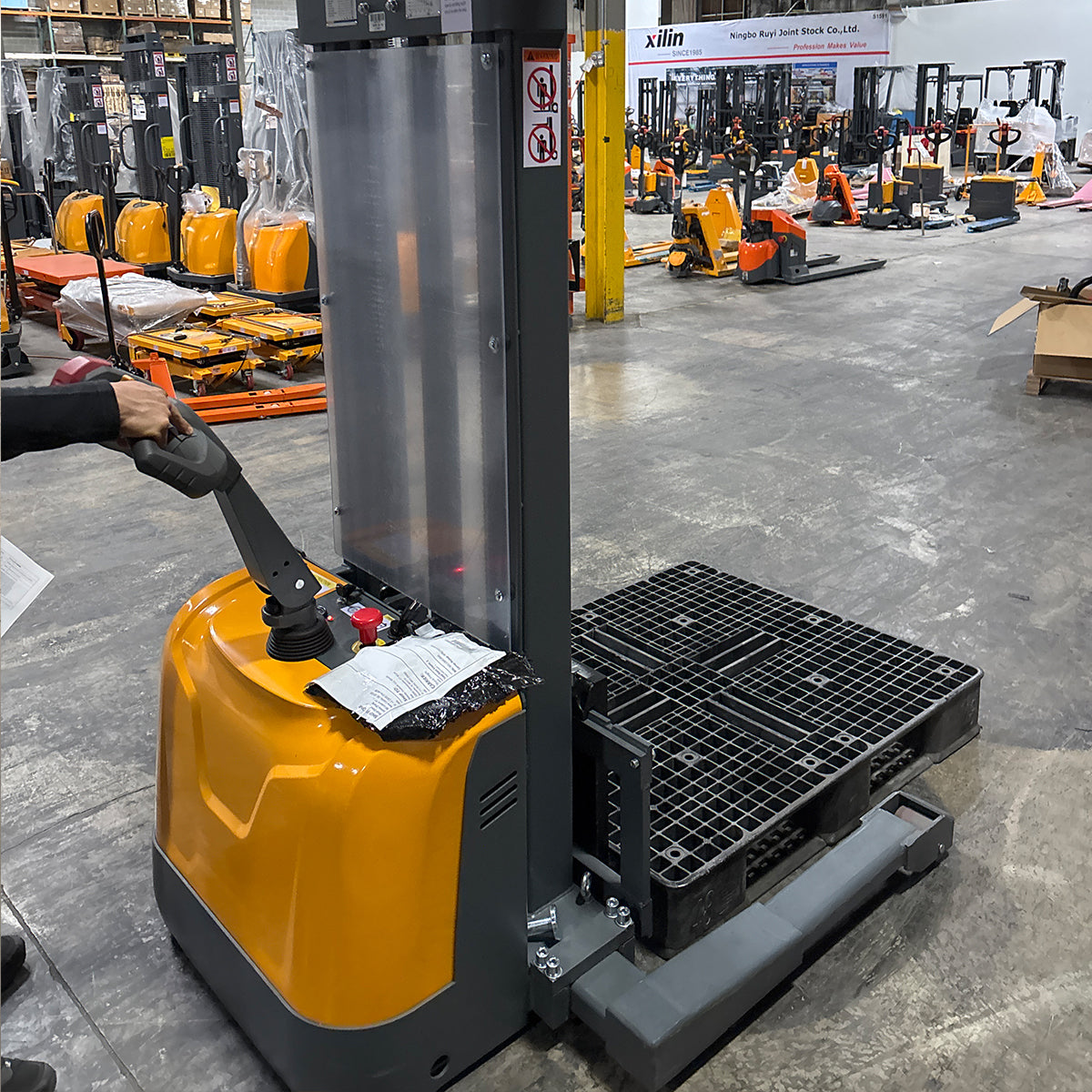 Yellow electric stacker base with control handle, keys, and access panel on top