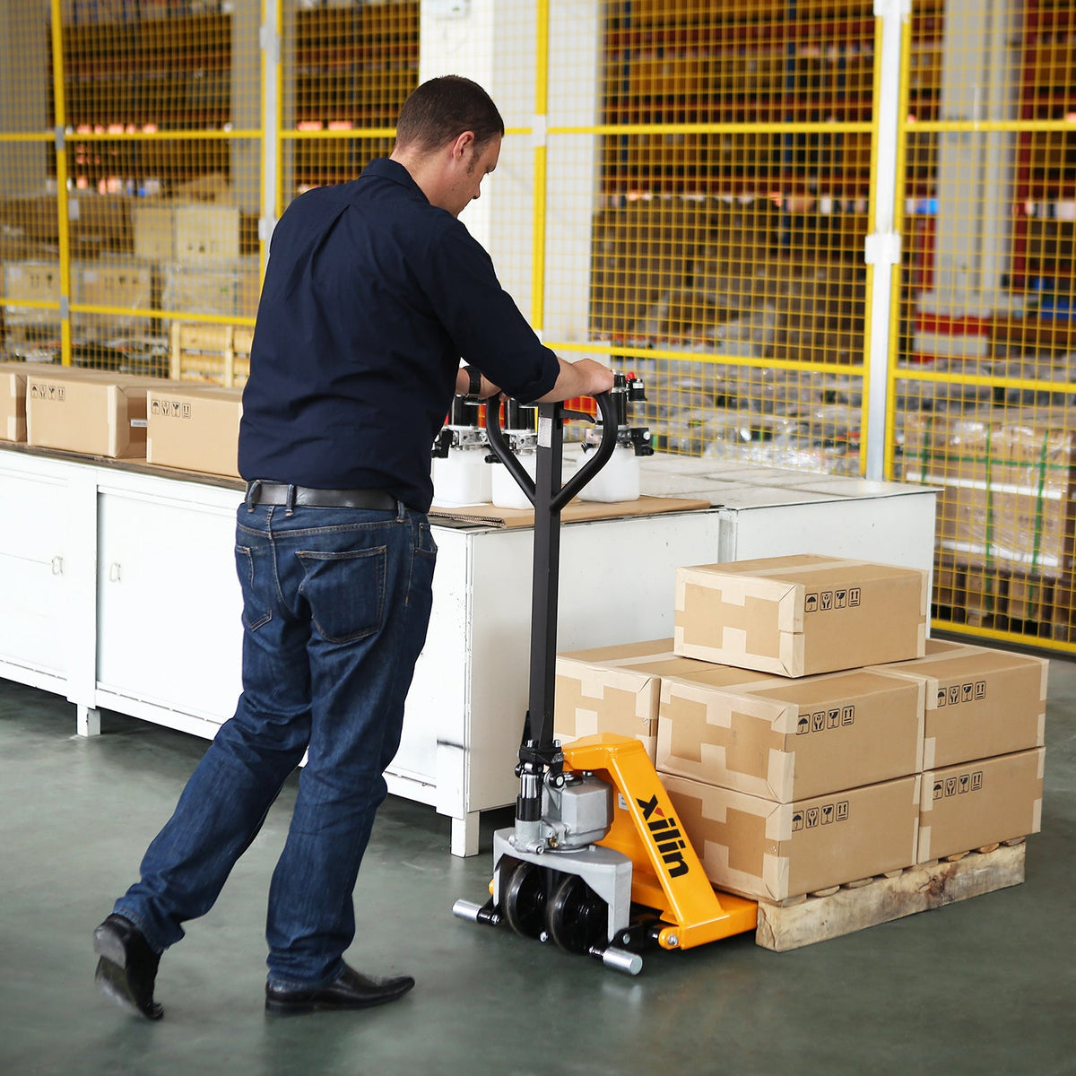 Operator pushing high lift pallet jack with yellow forks and black frame