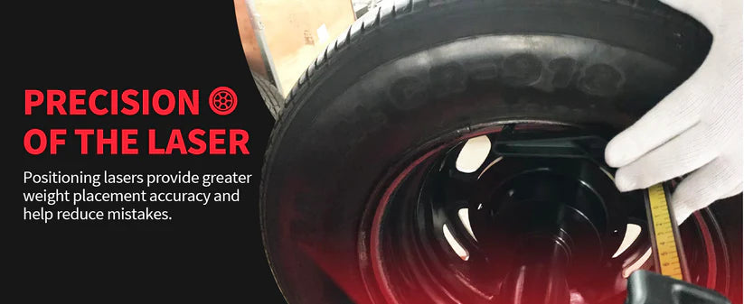 Wheel balancer laser head aiming at dark tire rim, gloved hands adjusting
