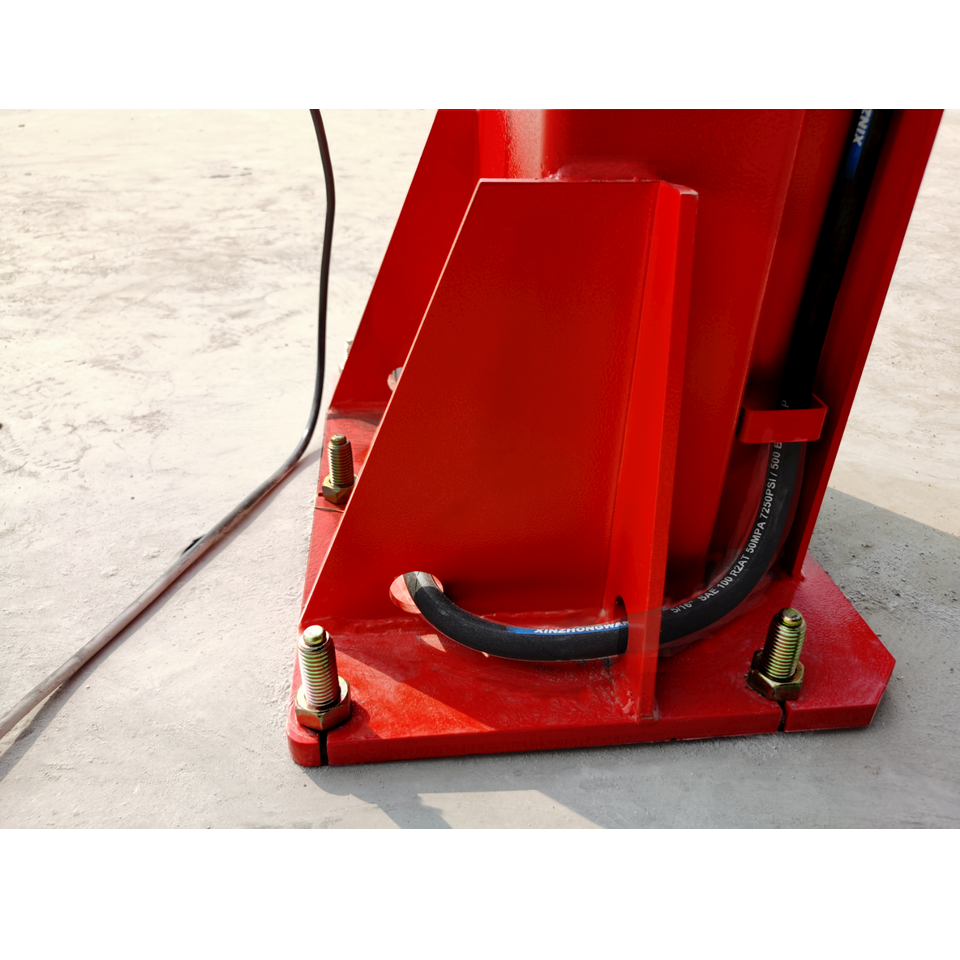 Car lift base plate with thick black cable and anchor bolts on red column