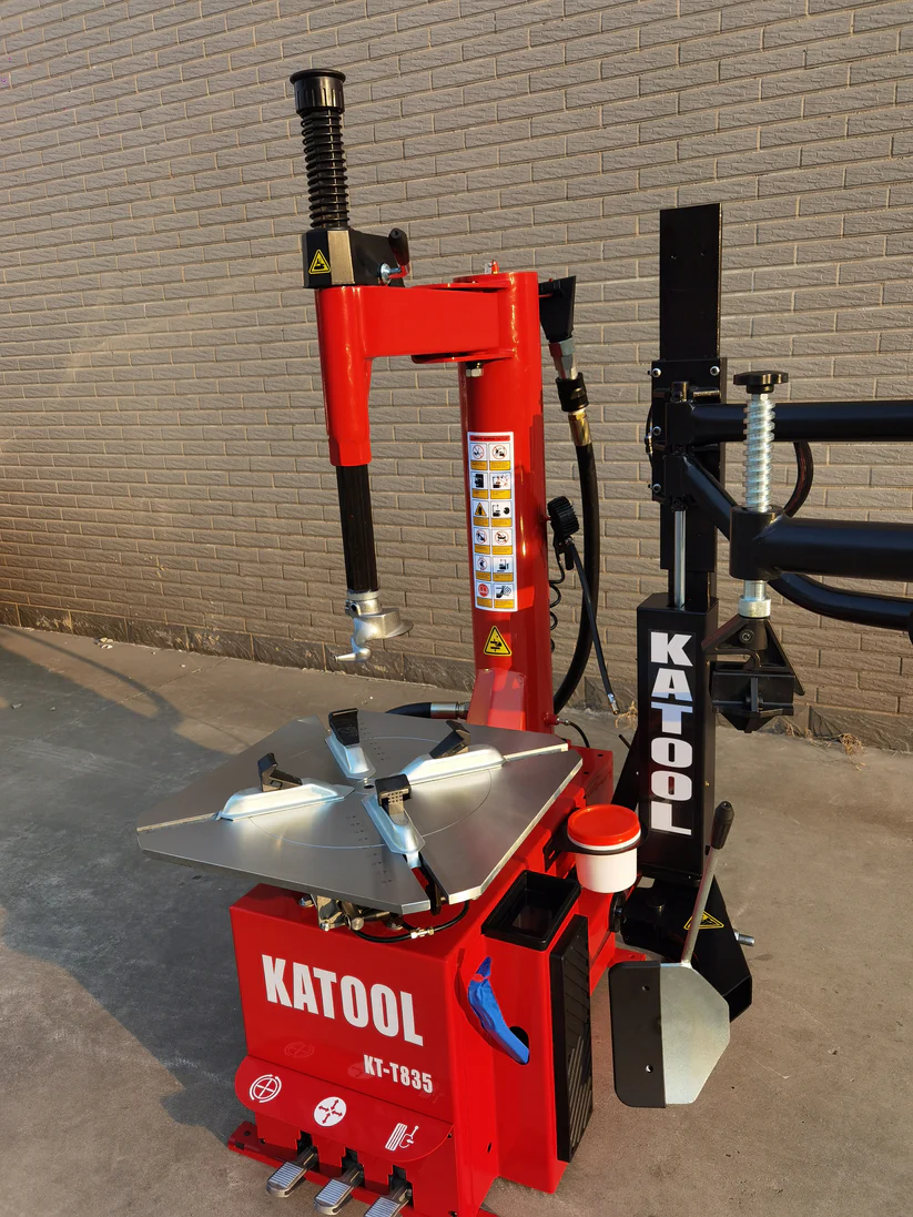 Tire changer machine with red housing, wide turntable, and vertical bead blaster post