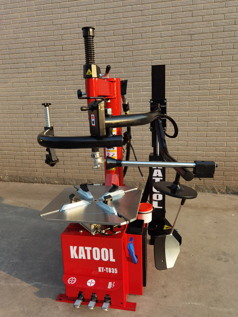 Red tire changer machine with double arms, mounting platform, and side guard