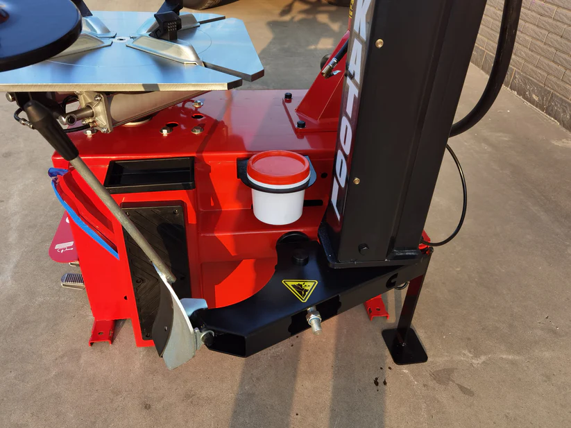 Tire changer control base with red housing, black bracket, and white cup holder