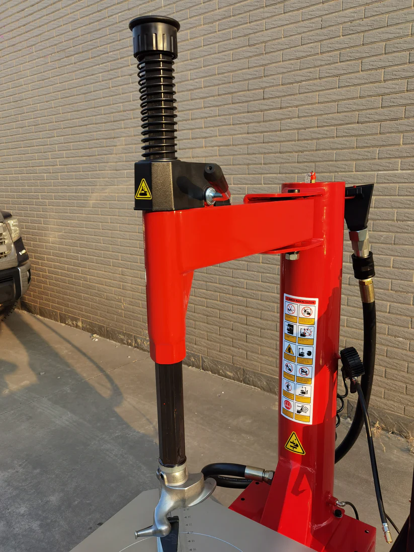 Tire changer bead blaster post with spring handle and vertical warning label