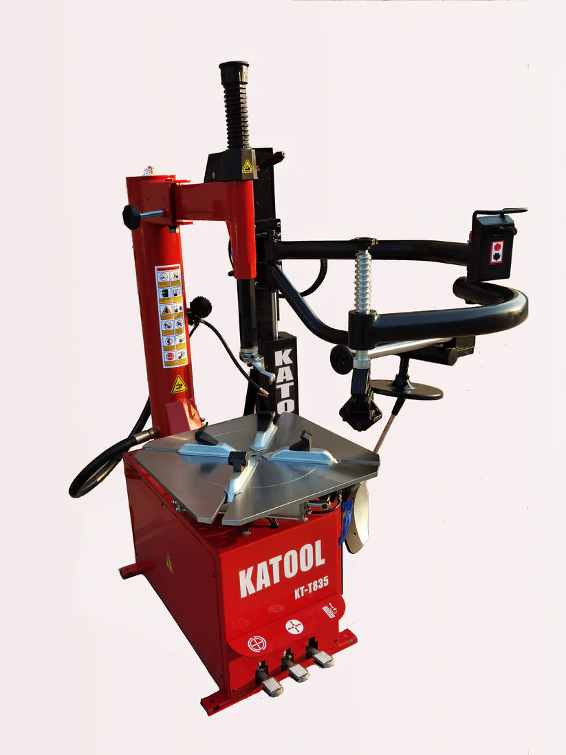 Tire changer with red base, black bead tool arms, and silver spring-loaded post