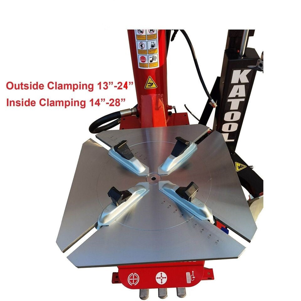 Tire changer base with four blue clamping tools on steel table
