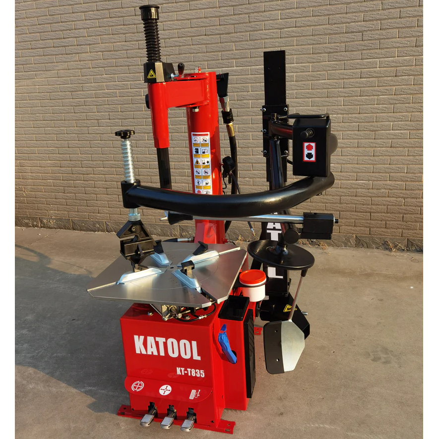 Double-arm tire changer with bead blaster and assist arm, red and black body on floor