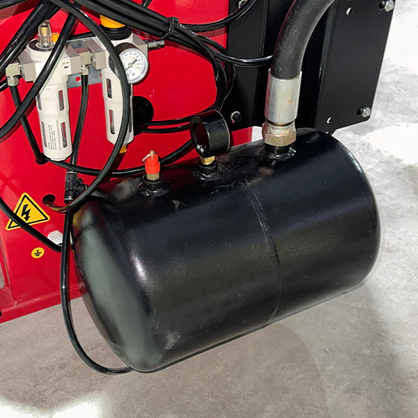 Pneumatic air tank with black cylinder and connected hoses on red tire press.