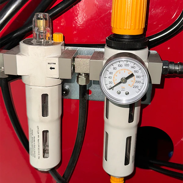 Air pressure regulator and gauge assembly on red tire press with hoses.