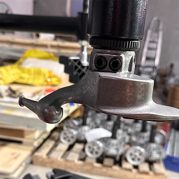 Metal tire-mounting shovel tip and bracket on vertical press, close-up.