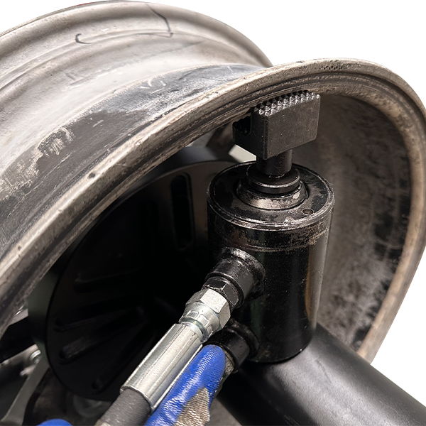 Hydraulic rim straightener arm with adjustment cylinder and connected hoses