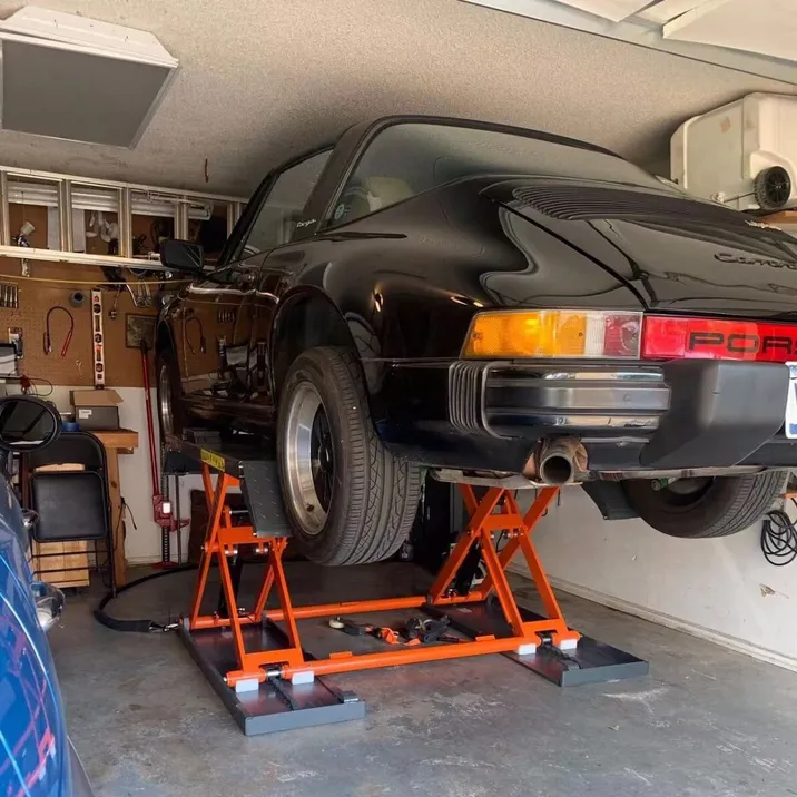 Pneumatic scissor lift holding a car on its orange frame platform supports