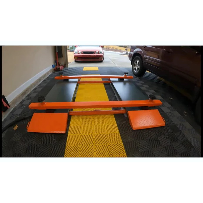 Pneumatic scissor lift with orange frame and textured platform pads in an indoor bay