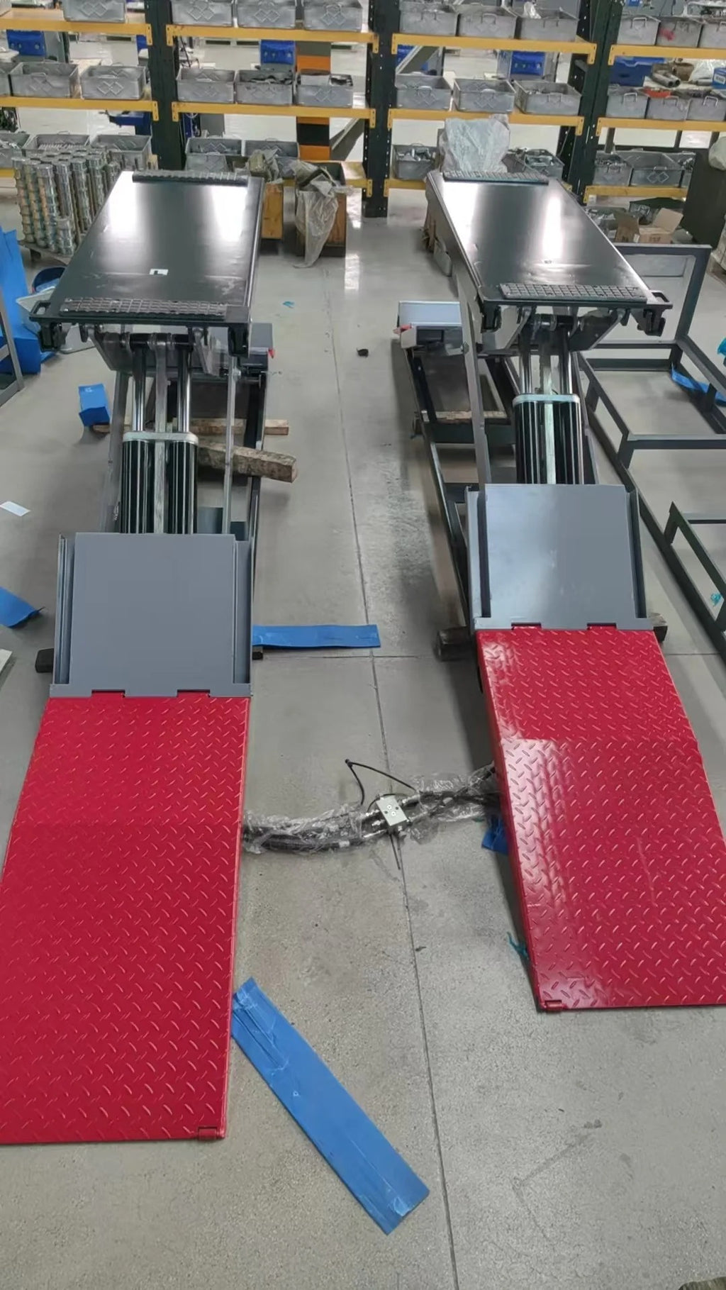 Pair of full-rise scissor lifts with gray platforms, hydraulic columns, and red base pads