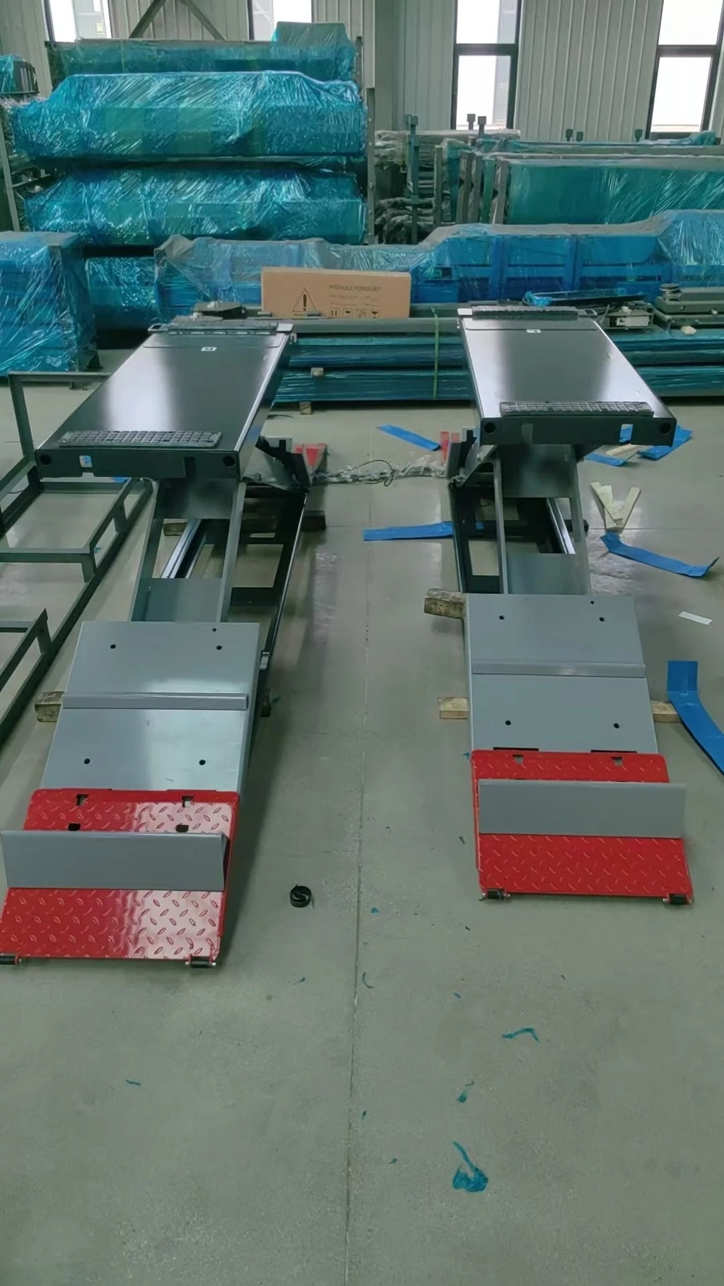 Workshop view of full-rise scissor lifts with gray platforms and red textured base pads