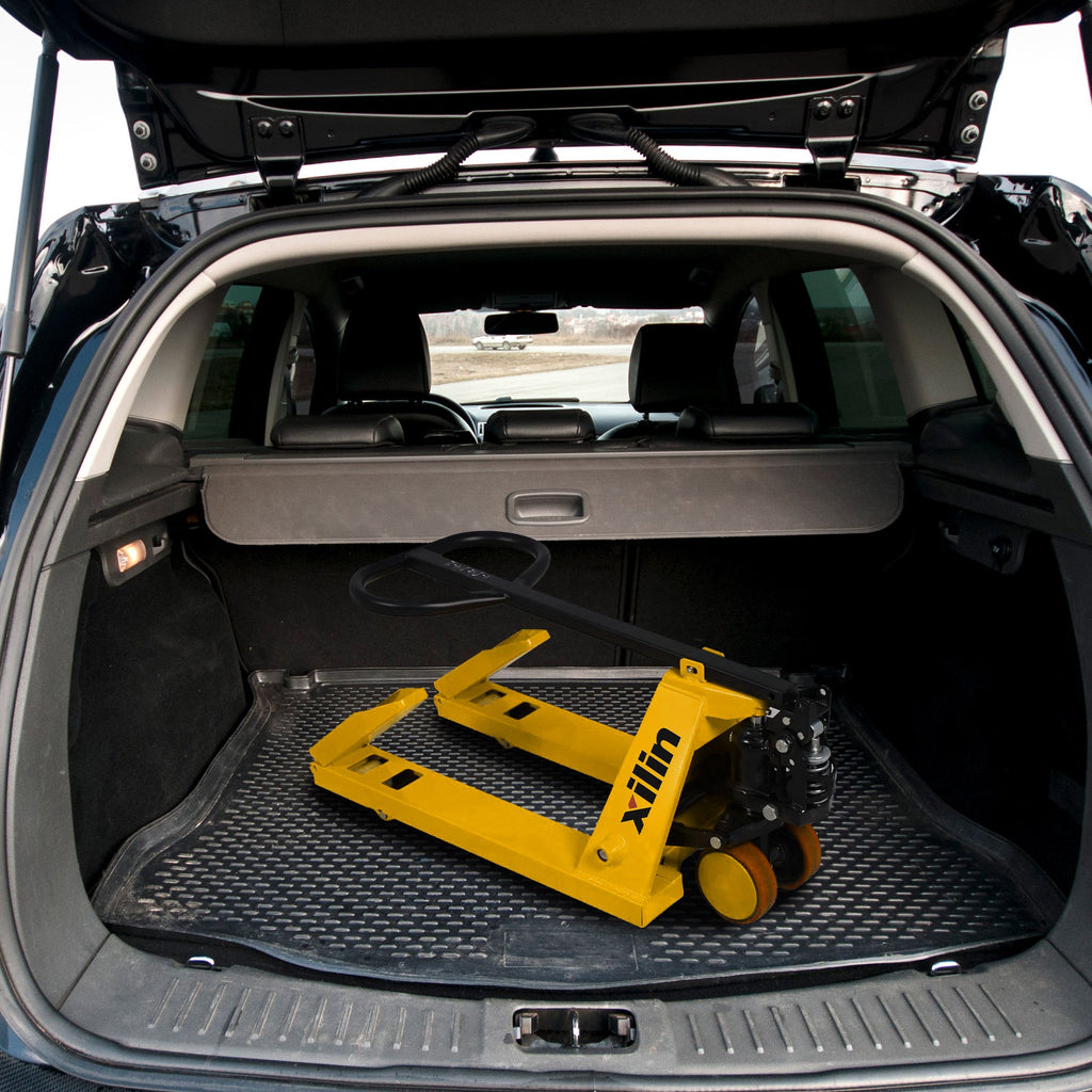 Manual pallet jack in vehicle trunk with yellow forks and black hydraulic pump