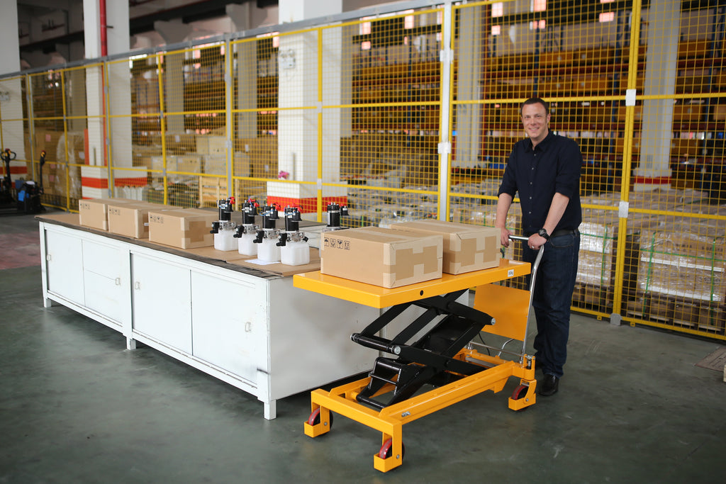 Orange lift table with raised platform and scissor legs, handle and caster wheels