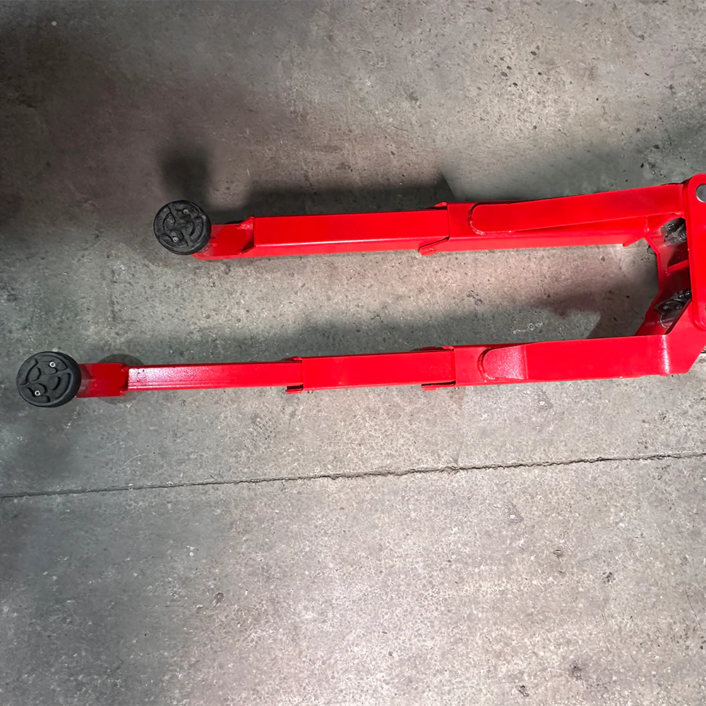 Red two-post lift arms with black roller pads on concrete floor