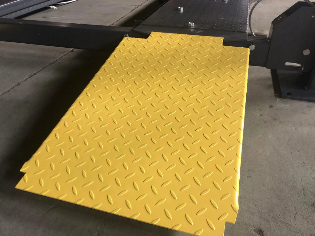 Yellow diamond-plate traction pad on the four-post parking lift platform