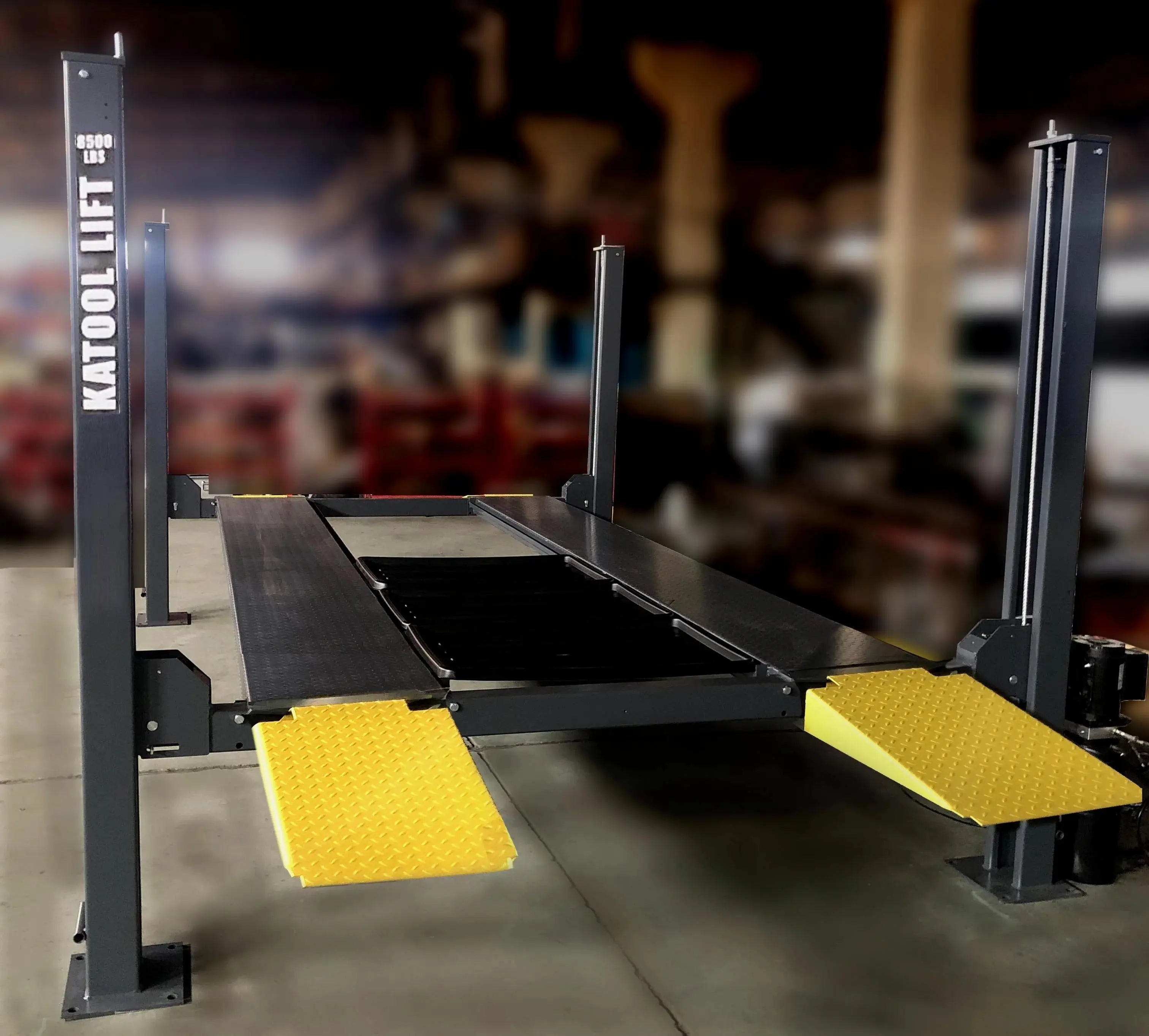 Four-post parking lift with black platforms and two yellow diamond traction pads