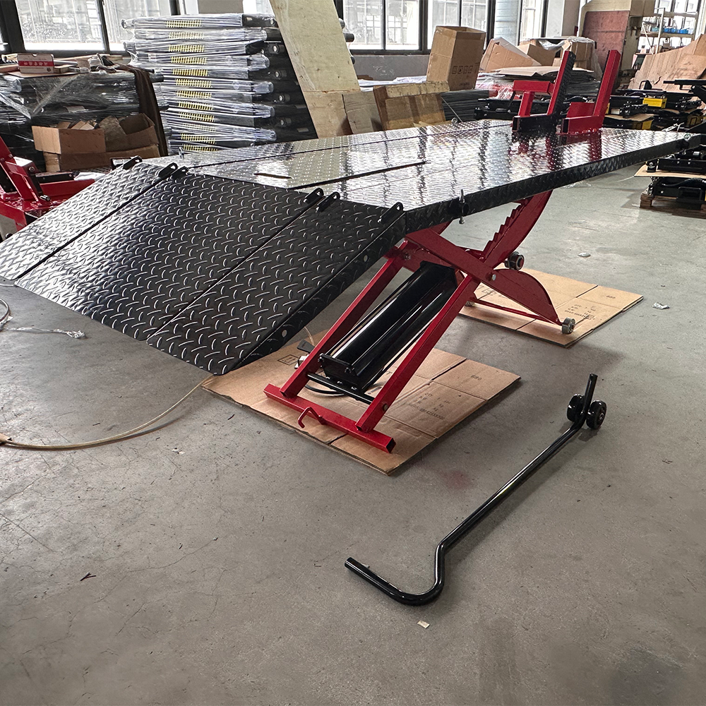 Hydraulic motorcycle lift in warehouse with extended ramps and red scissor frame